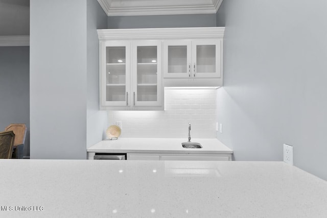 kitchen featuring white cabinetry, decorative backsplash, ornamental molding, and sink