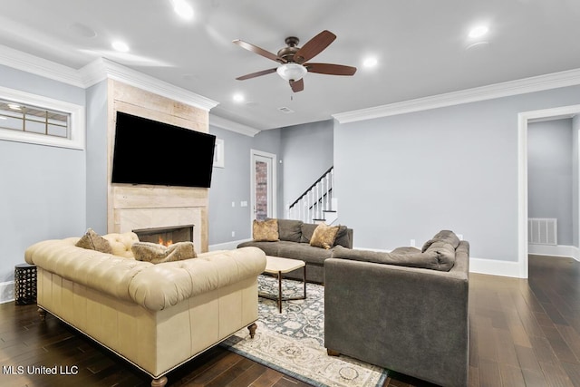 living room with ceiling fan, dark wood-type flooring, ornamental molding, and a fireplace