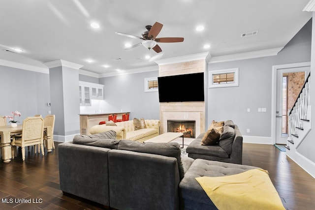 living room featuring ceiling fan, dark wood-type flooring, a tile fireplace, and ornamental molding