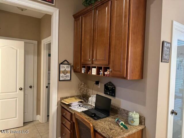 kitchen featuring built in desk, light tile patterned floors, and light stone countertops