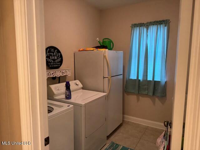 clothes washing area with independent washer and dryer and light tile patterned floors