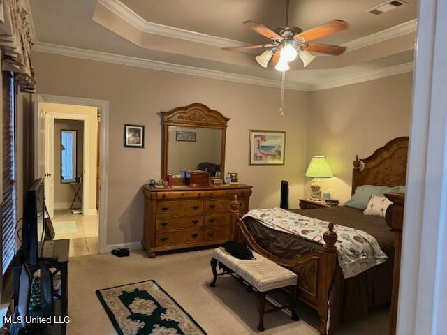 bedroom with ceiling fan, ornamental molding, a raised ceiling, and light carpet