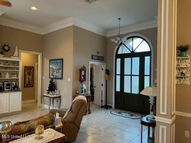 tiled foyer entrance with crown molding and a notable chandelier