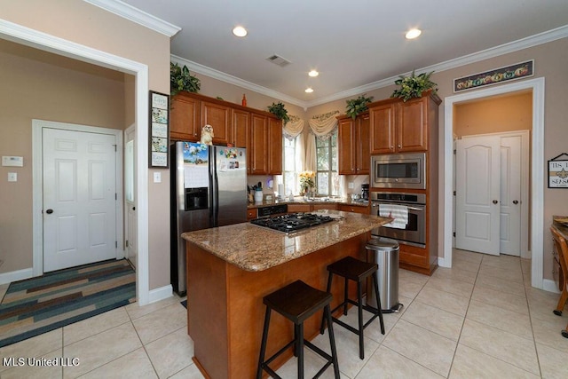 kitchen featuring light stone counters, crown molding, a center island, light tile patterned floors, and appliances with stainless steel finishes