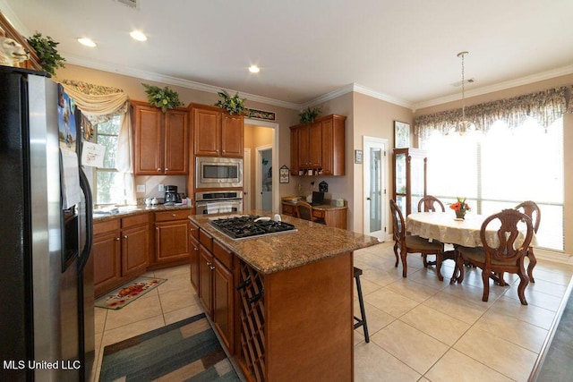 kitchen with hanging light fixtures, appliances with stainless steel finishes, a center island, and plenty of natural light