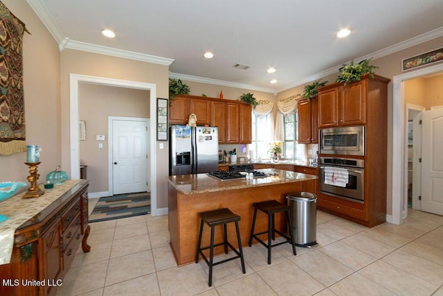 kitchen featuring a breakfast bar area, a kitchen island, stainless steel appliances, light stone counters, and light tile patterned flooring