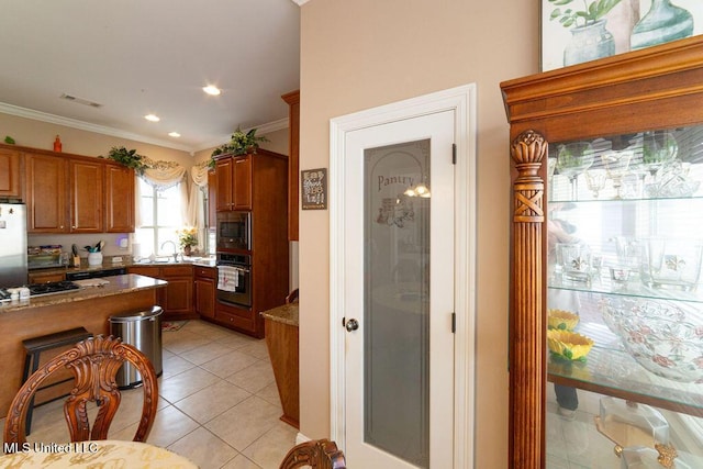 kitchen featuring stainless steel appliances, light tile patterned flooring, light stone countertops, and ornamental molding