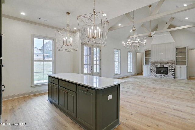 kitchen featuring a fireplace, light hardwood / wood-style floors, a kitchen island, and hanging light fixtures