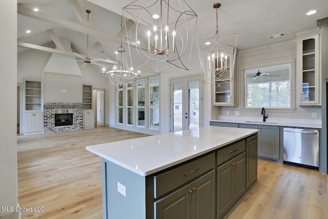 kitchen with a brick fireplace, pendant lighting, light hardwood / wood-style flooring, dishwasher, and a kitchen island