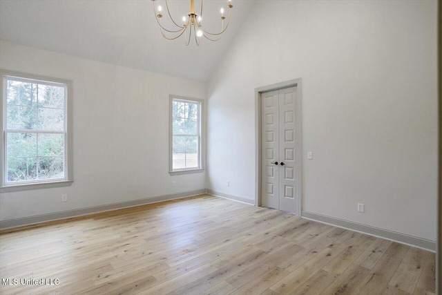 spare room featuring plenty of natural light, high vaulted ceiling, and light hardwood / wood-style flooring