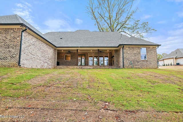 back of property featuring a lawn and ceiling fan