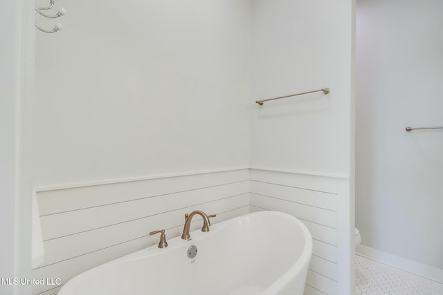 bathroom featuring tile patterned floors, a freestanding tub, and toilet