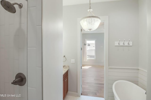 full bathroom featuring a soaking tub, an inviting chandelier, vanity, and a tile shower