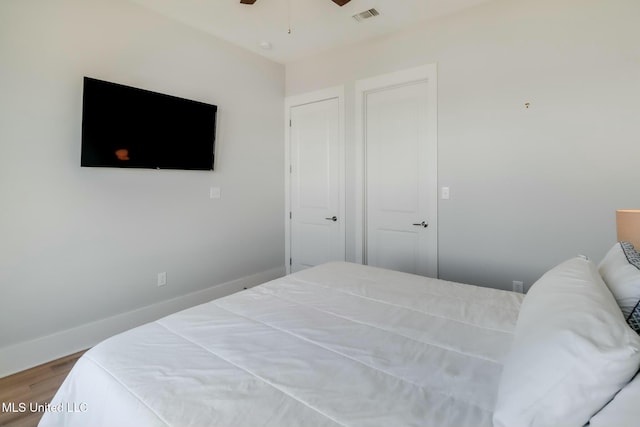 bedroom with wood finished floors, baseboards, visible vents, and ceiling fan