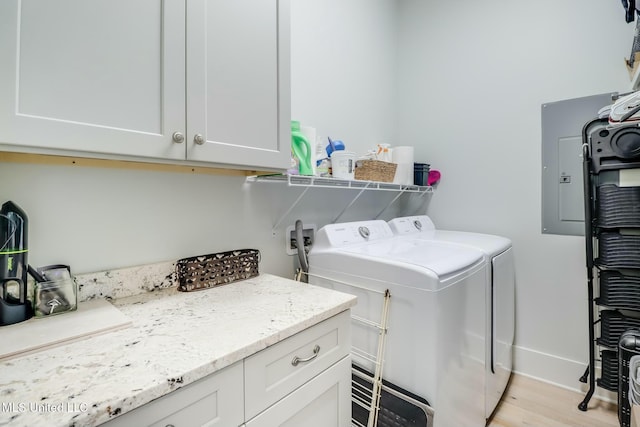 laundry area featuring washer and dryer, cabinet space, light wood-style floors, and baseboards