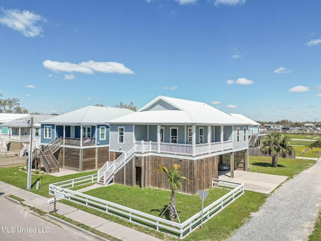 view of front of house with stairs, gravel driveway, a front lawn, and fence