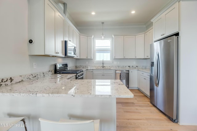 kitchen with light wood-type flooring, pendant lighting, a sink, stainless steel appliances, and a peninsula