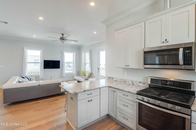 kitchen featuring ornamental molding, open floor plan, recessed lighting, stainless steel appliances, and a peninsula