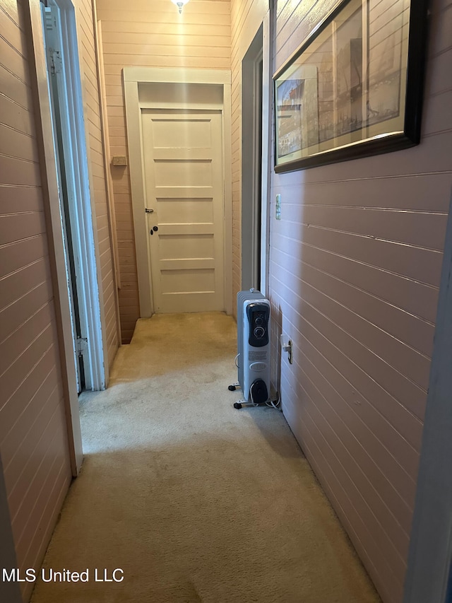 hallway featuring light colored carpet and wooden walls