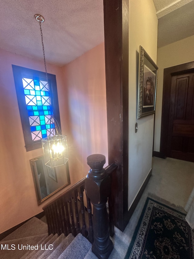 interior space featuring a textured ceiling, an inviting chandelier, and carpet floors