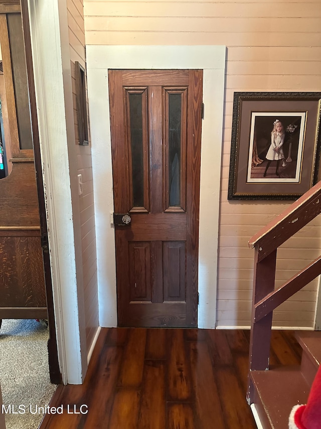 interior space with dark hardwood / wood-style flooring and wooden walls