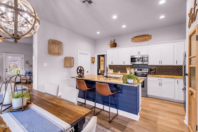 18109 Evergreen Dr, Gulfport, MS 39503 - kitchen featuring appliances with stainless steel finishes, tasteful backsplash, white cabinets, light stone countertops, and recessed lighting