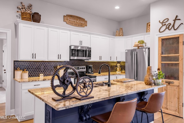 18109 Evergreen Dr, Gulfport, MS 39503 - kitchen featuring appliances with stainless steel finishes, a breakfast bar, white cabinets, decorative backsplash, and recessed lighting