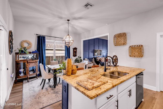 18109 Evergreen Dr, Gulfport, MS 39503 - kitchen with stainless steel dishwasher, a chandelier, light wood-style floors, white cabinets, and light stone countertops