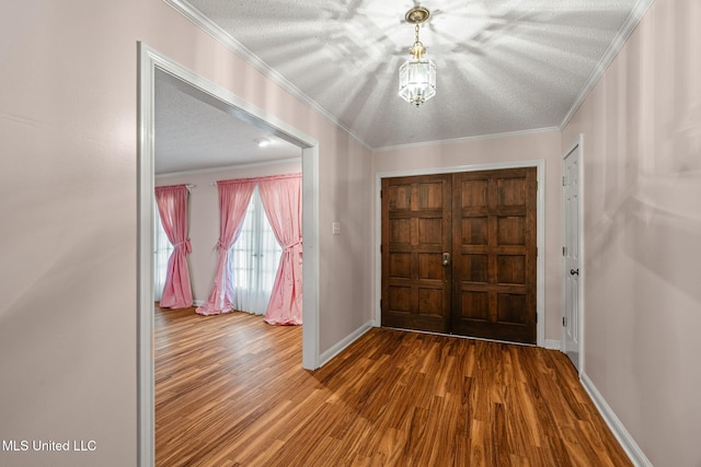 foyer featuring crown molding, baseboards, wood finished floors, and a textured ceiling