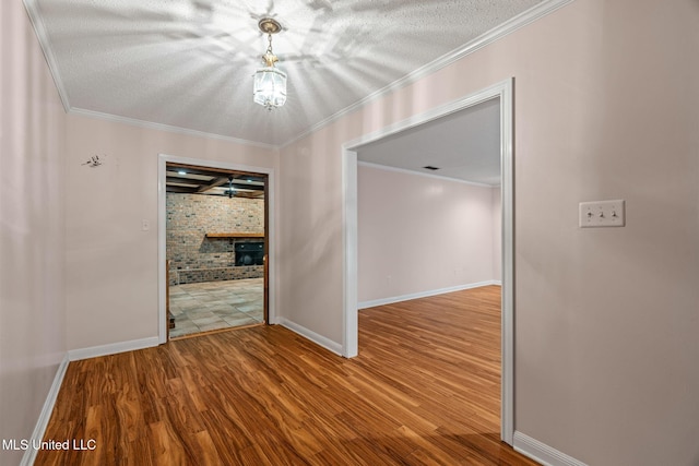 empty room with ornamental molding, baseboards, wood finished floors, and a textured ceiling