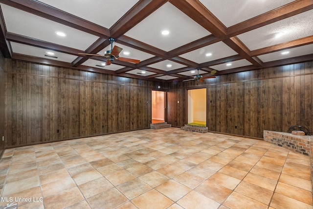 unfurnished room featuring wooden walls, beam ceiling, coffered ceiling, and ceiling fan