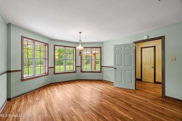unfurnished dining area with wood finished floors, baseboards, and ornamental molding