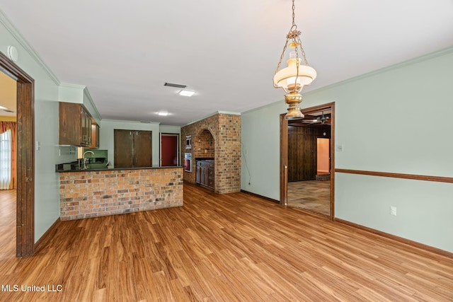 interior space featuring visible vents, baseboards, ornamental molding, a fireplace, and light wood-style flooring