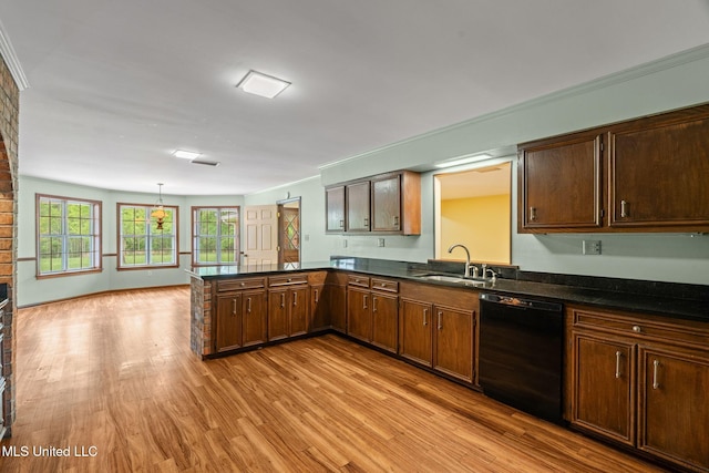 kitchen featuring dishwasher, a sink, dark countertops, a peninsula, and light wood finished floors