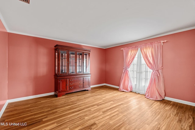 empty room with ornamental molding, baseboards, and light wood-type flooring