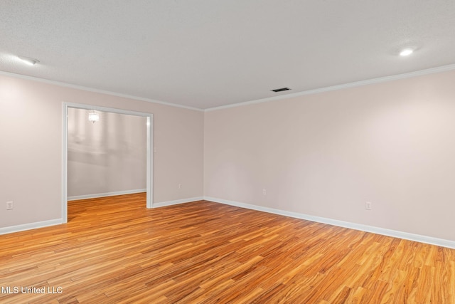 spare room featuring ornamental molding, visible vents, baseboards, and light wood-type flooring