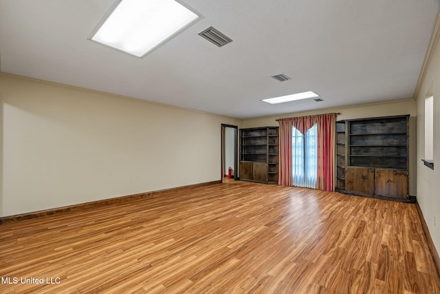 empty room featuring visible vents, baseboards, and light wood-type flooring