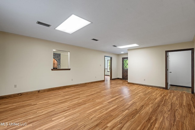 spare room with light wood-style floors, visible vents, and baseboards