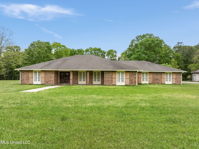 ranch-style home with roof with shingles, a front yard, brick siding, and french doors