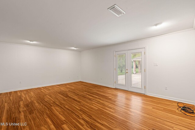 spare room with ornamental molding, visible vents, baseboards, and wood finished floors