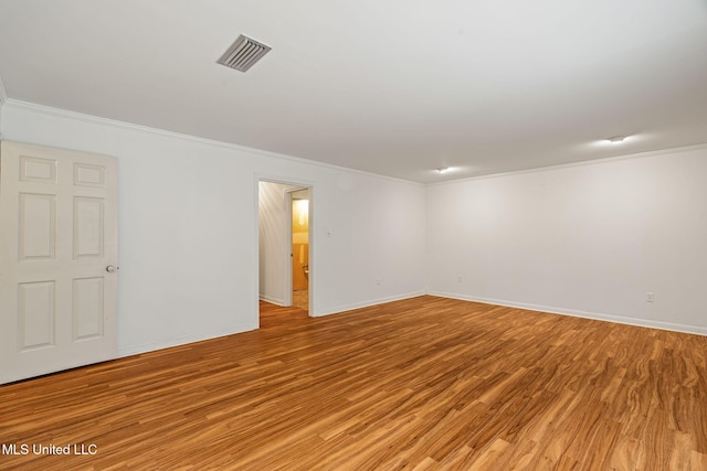 spare room featuring baseboards, visible vents, light wood-type flooring, and crown molding