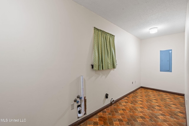 interior space featuring electric panel, baseboards, laundry area, and a textured ceiling