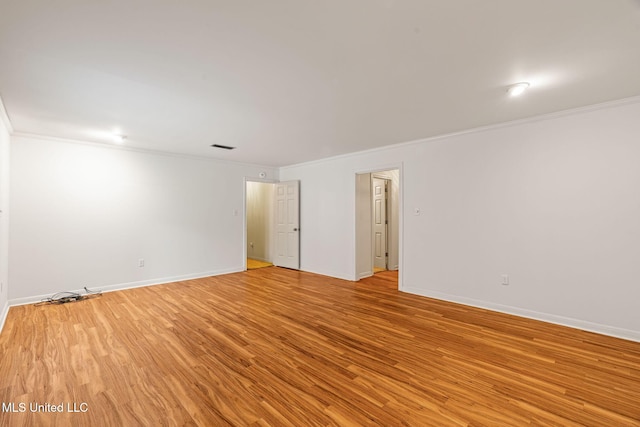 spare room with ornamental molding, baseboards, light wood-type flooring, and visible vents