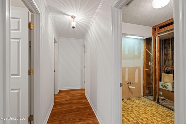 hall featuring visible vents, baseboards, wood finished floors, and a textured ceiling
