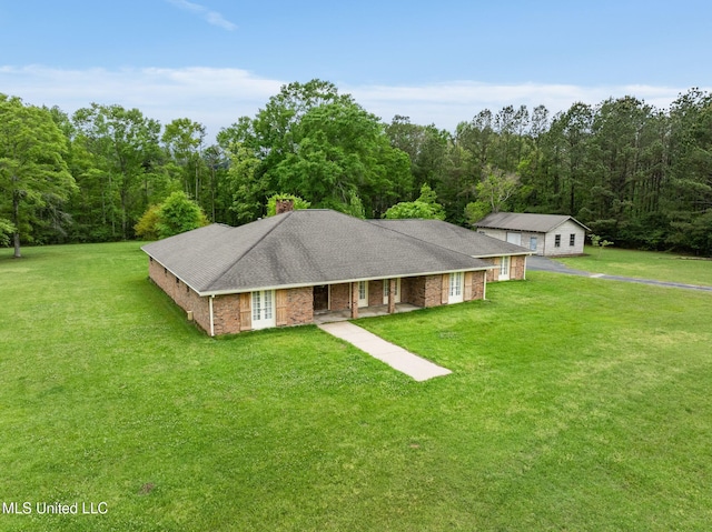 view of front of property with a front yard, a forest view, a shingled roof, and brick siding