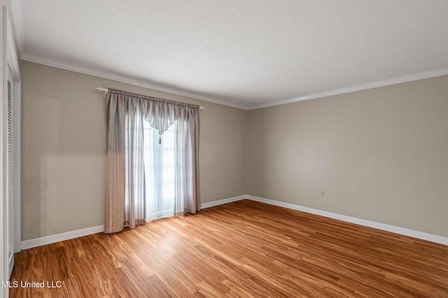 unfurnished room with a textured ceiling, baseboards, ornamental molding, and wood finished floors