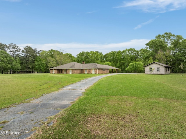 ranch-style home with driveway, a chimney, and a front lawn