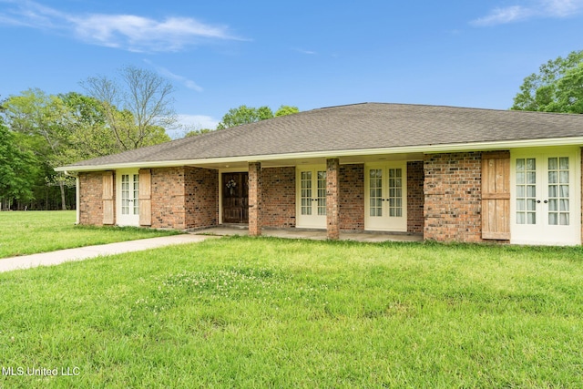 ranch-style house featuring a front yard, french doors, a shingled roof, and brick siding