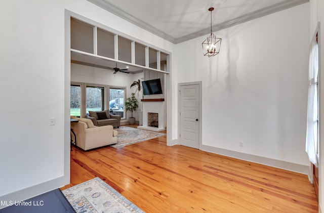 living room featuring ornamental molding, ceiling fan with notable chandelier, and hardwood / wood-style flooring