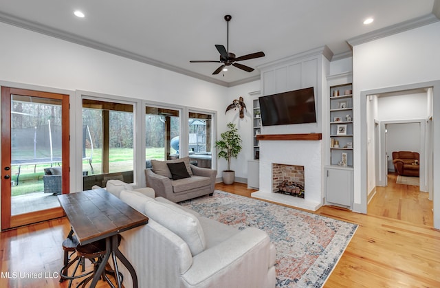 living room with ceiling fan, built in features, ornamental molding, and light hardwood / wood-style flooring